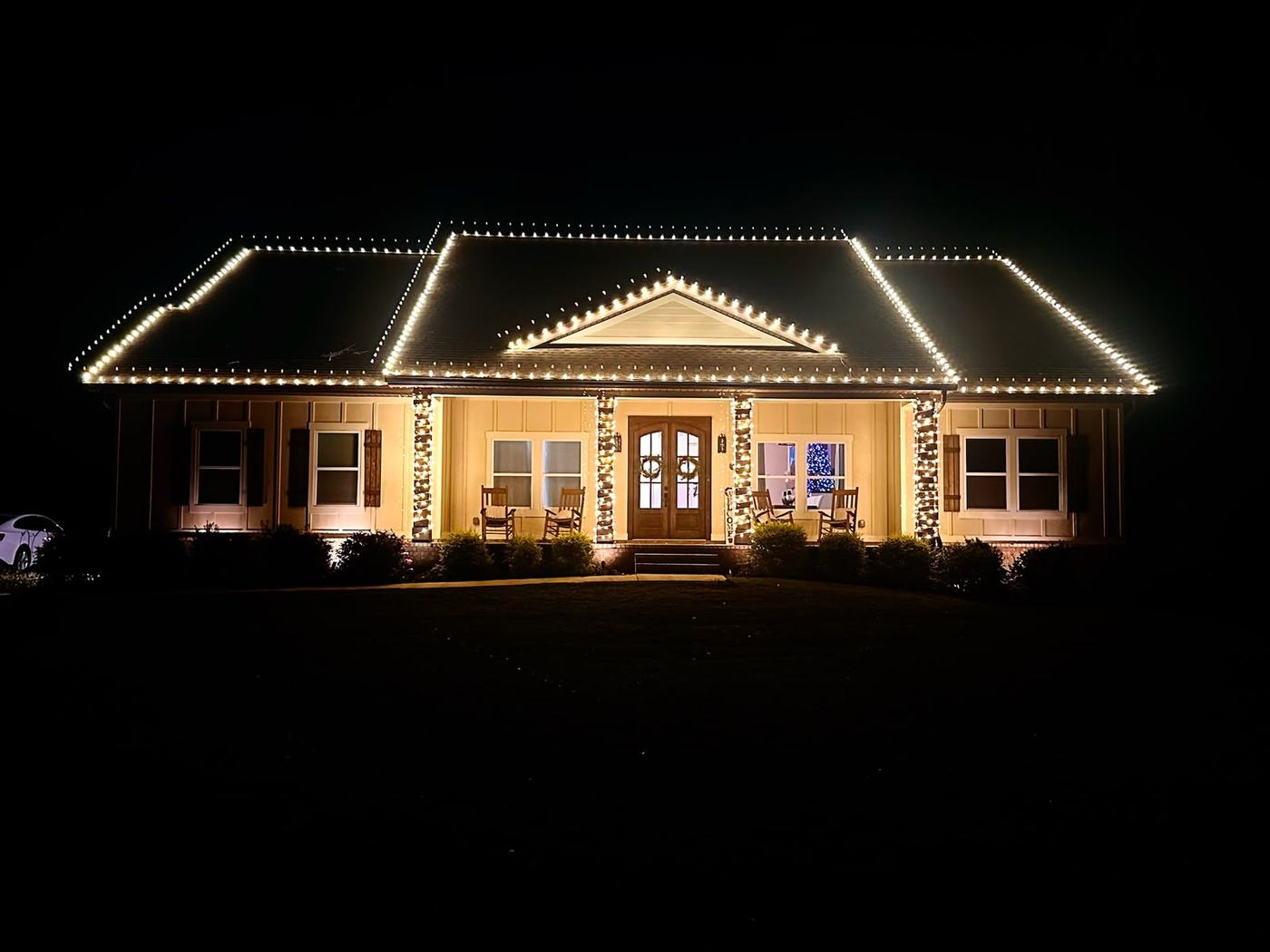 Warm white roofline and porch column lighting on a single-story home