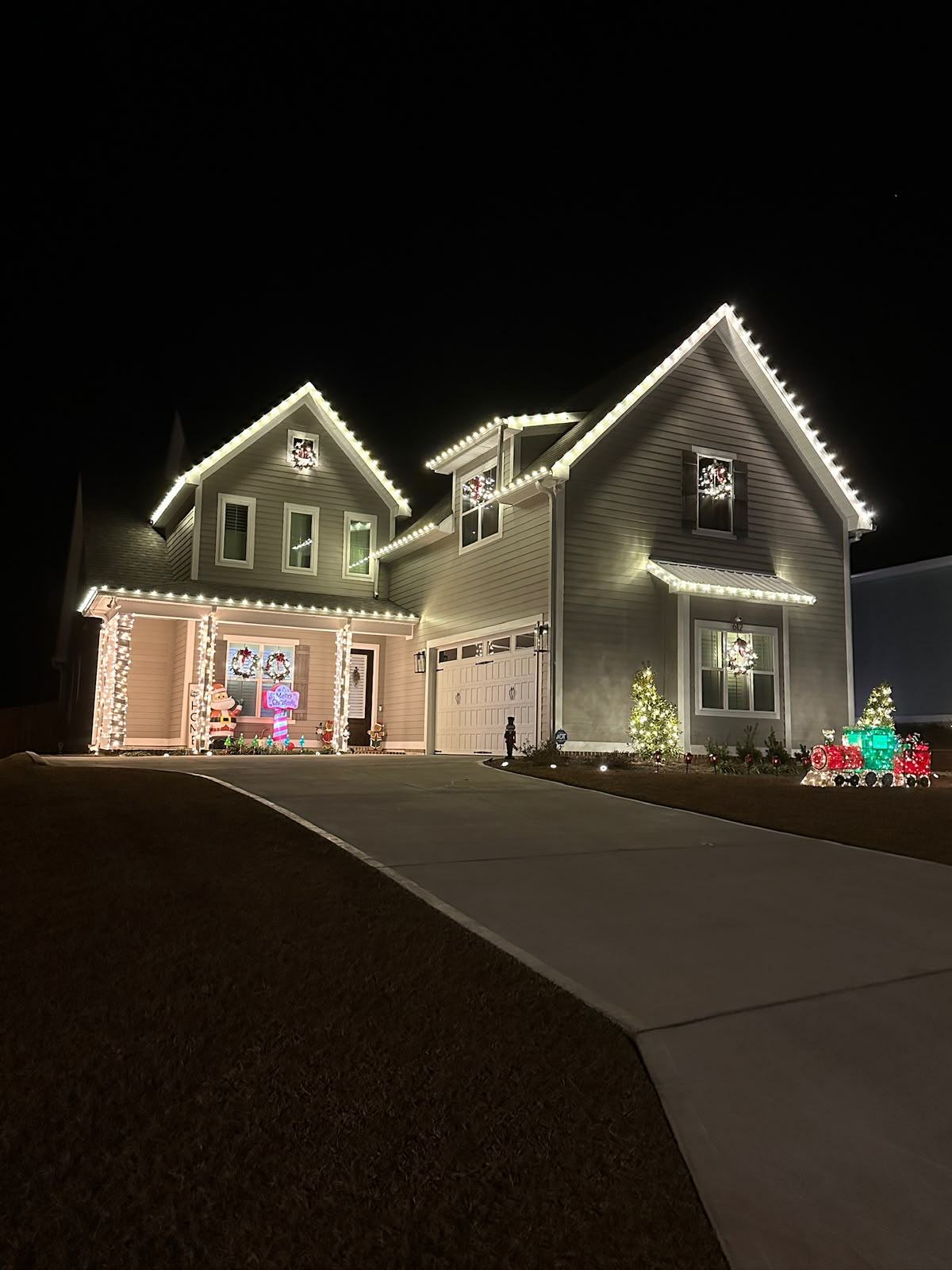 Warm white roofline lighting with wreaths on a two-story home